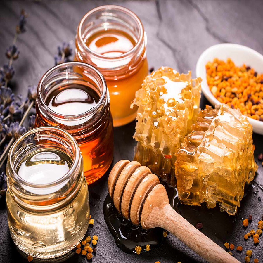 imagen de tres tarros de diferentes tipos de miel con un panal con miel